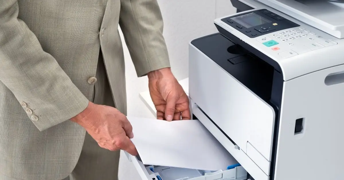 Gestor manuseando papel em impressora corporativa em artigo sobre outsourcing de impressão para PME da região de POA
