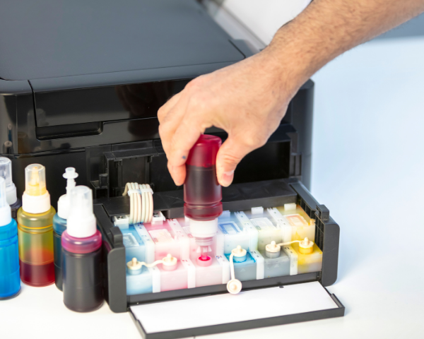 Profissional realizando recarga de tinta em impressora com sistema de reservatórios coloridos