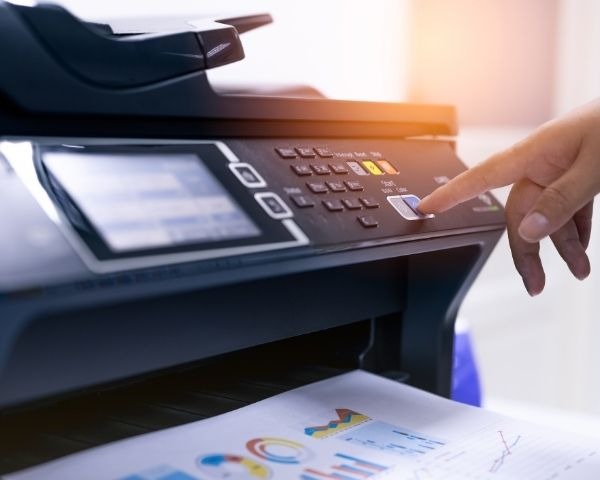 Impressora multifuncional realizando impressão colorida em ambiente empresarial