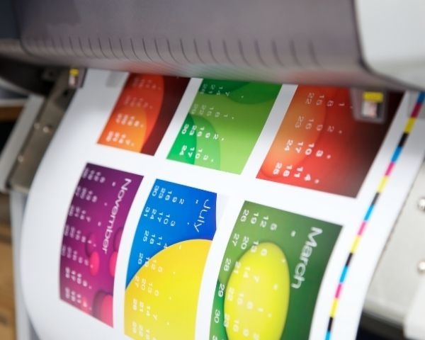 Impressora produzindo material gráfico colorido para eventos e ações promocionais
